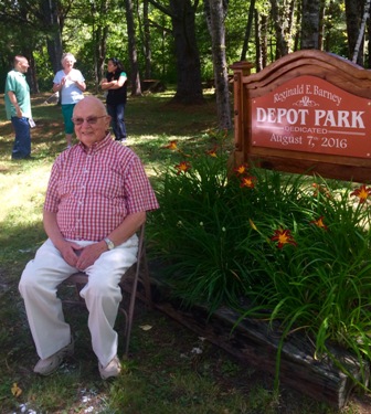 Reggie Barney sitting next to new sign.