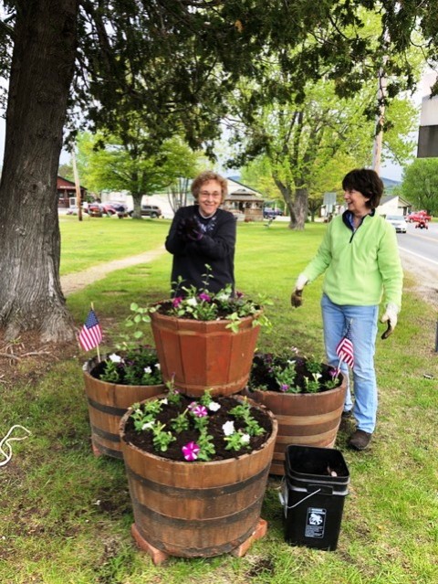 two women with tree barrels of flowers