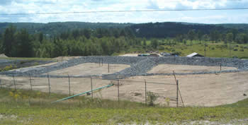 Construction crew shaping stone mounds for rapid infiltration bed pits.