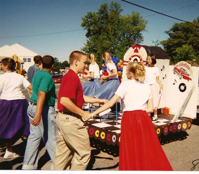 parade float surrounded by dancers in 50s costumes