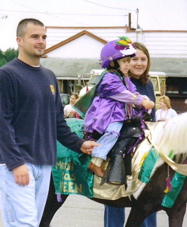 child dressed in mardi gras costume on pony
