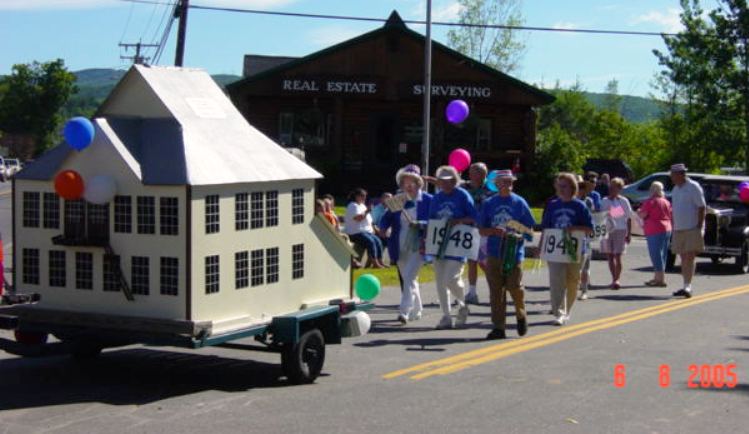 1948 alumni marching behind float of the old high school model