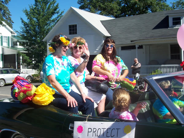 alumni dressed as hippies waving from a classic car