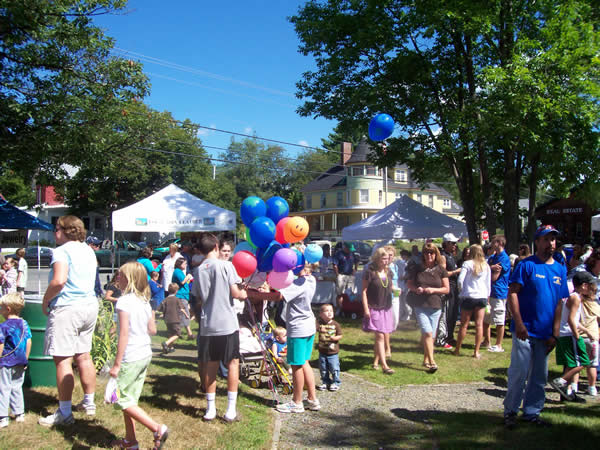 people shopping and walking among vendor tents