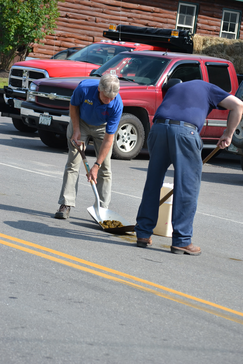 two men shoveling dung from roadway