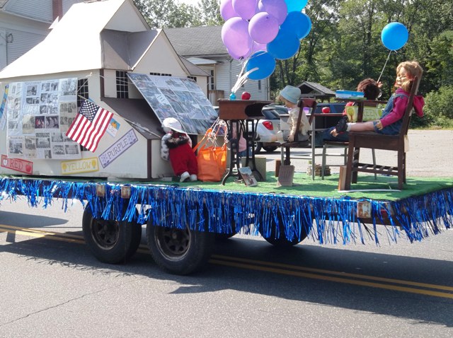 model of old high school being pulled as a float